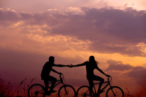 ερωτευμένο ζευγάρι που κάνει ποδήλατο στο ηλιοβασίλεμα